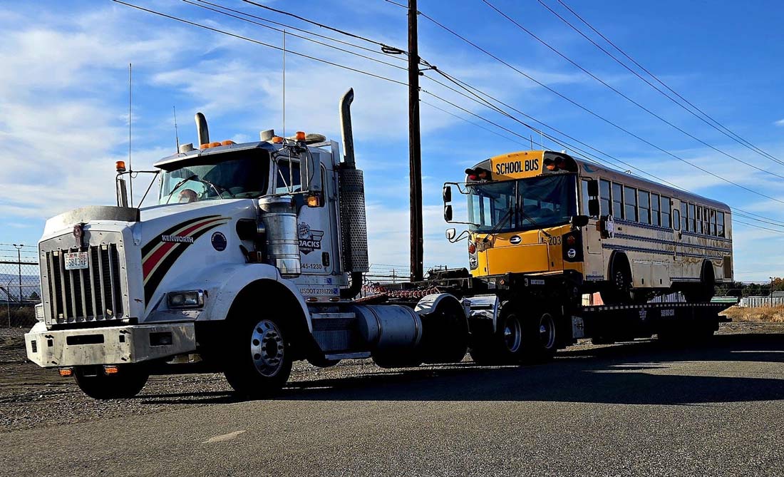 A Jacks Towing Heavy Duty Truck with Bus on Landoll for transport
